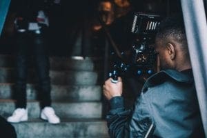 A camera operator filming people on steps. Used on our Filmmaking Resources page.