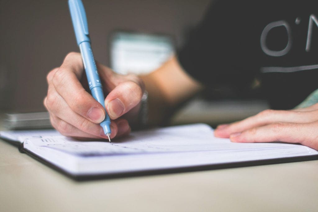 Go Basic to Go Bigger: 5 Tips For a Great Producible Film Concept 2 canva person holding blue ballpoint pen writing in notebook